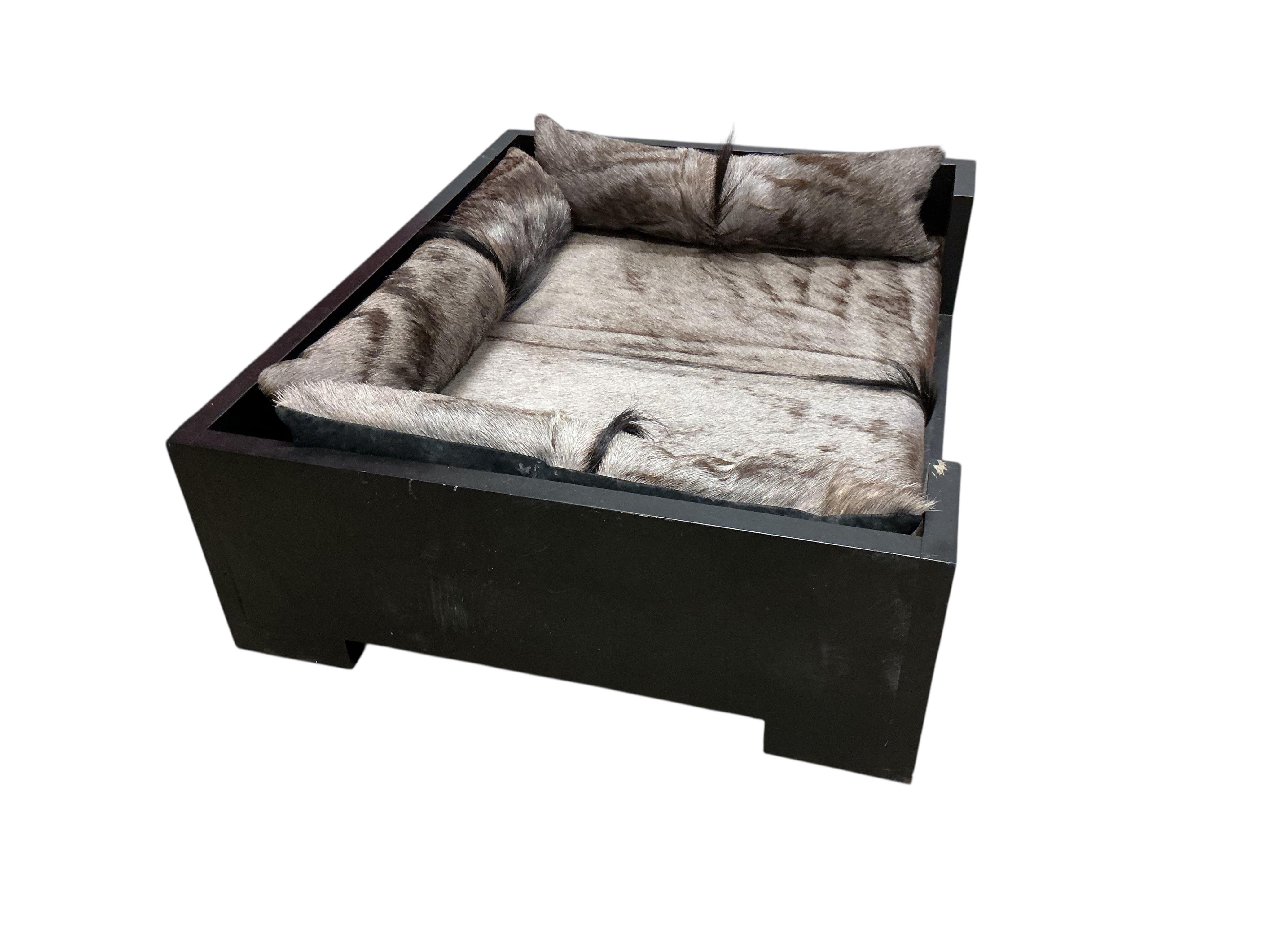 A contemporary ebonised dogs bed with faux fur cushions, width 97cm, depth 77cm, height 29cm